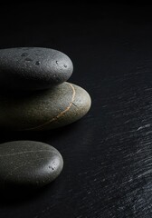 Collection of smooth, wet river stones placed on a reflective dark slate, emphasizing texture, contrast, and calm simplicity, stacked, space, geology
