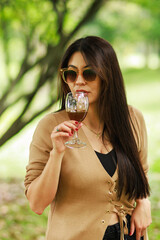 Woman enjoying a drink in a park with sunglasses