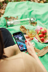 Woman taking a photo with her smartphone during a picnic outdoors