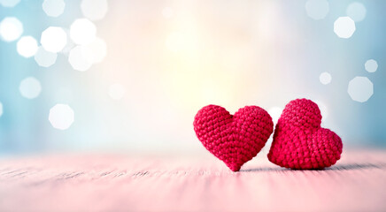 Two red heart shapes sit closely together on a blue glitter background. Valentine's day.