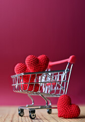 The red Heart shapes in shopping cart on red background , love concept for shopping on valentines day