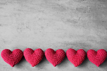 Valentine's Day. Red knitted hearts on a grey background. Flat lay.