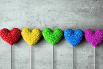 Valentine's Day. Multicolored knitted hearts on a stick on grey background. Flat lay.