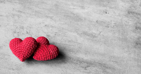 Two red heart shapes sit closely together on a grey background. Valentine's day.