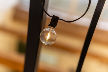 Light bulb hanging from a metal fixture with soft background lighting
