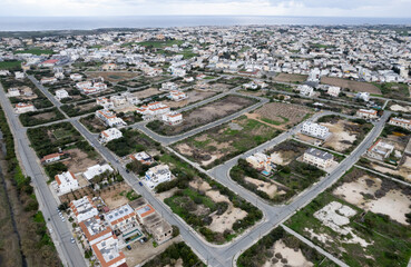 Aerial view of residential area with empty lots and scattered houses in a coastal landscape. Protaras, Cyprus