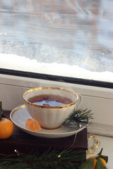 A mug of hot black tea on the windowsill. Christmas atmosphere.