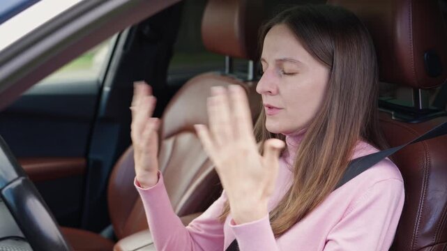 Worried woman in car waves hands in distress, suffering from shortness of breath, panic attack, tachycardia, and stress while sitting in the driver seat. Breathing issues