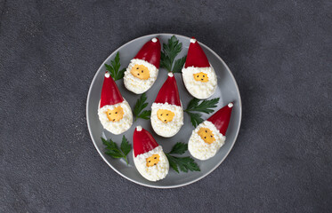 Stuffed eggs in shape of Santa Claus on gray plate