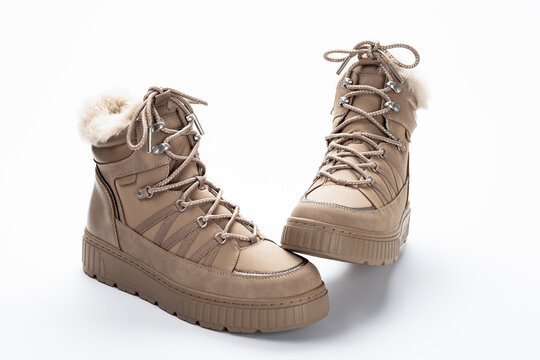 Beige winter boots with faux fur lining and lace-up design photographed in studio on a white background, showing warm outdoor footwear style and materials for commercial use.