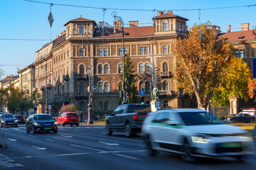 Fototapeta premium View of city streets, architecture, houses and traffic, random people on the sidewalk, city life in Budapest, Hungary, Heroes Square