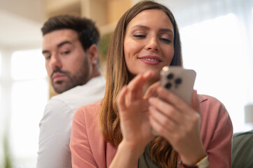 Man feeling jealous watching woman using phone