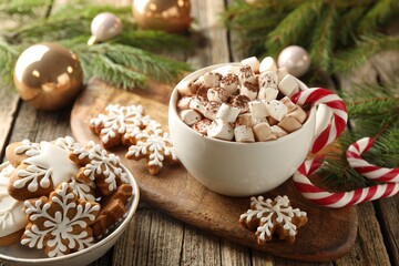 Tasty cocoa, marshmallows, candy canes, gingerbread cookies and Christmas decor on wooden table, closeup