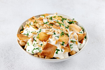 Middle Eastern chickpea Fatteh with yogurt, toasted pita bread, pine nuts. Traditional Levantine breakfast dish.