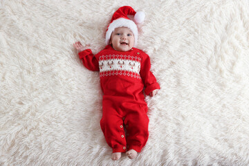 Cute little baby in Santa hat on fluffy blanket, top view. Christmas season