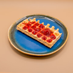 Waffle with strawberry jam on blue plate