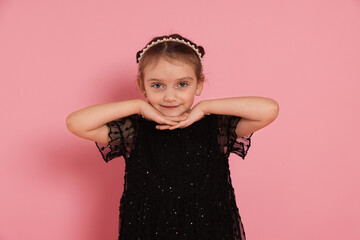 Portrait of cute little girl in headband and dress on pink background