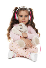 Cute little girl in headphones with toy rabbit sitting on white background
