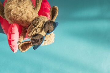 Knitted Plush Sheep in Sunglasses on Pink Flamingo Float Against Blue Background. Top view