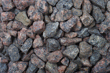 Gravel rocks in various colors collected from a construction site. Granite stones vary in size and are used for paving roads and in construction.