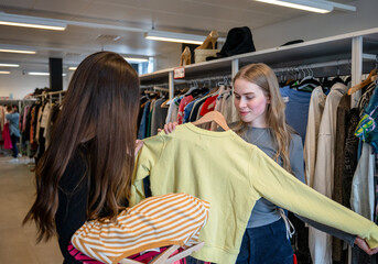 Women choosing clothes together in secondhand store
