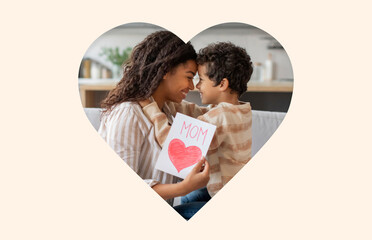 A joyful scene of a mother and her young son sharing a tender moment at home. The child holds a handmade card while they smile at each other, capturing their bond and affection.