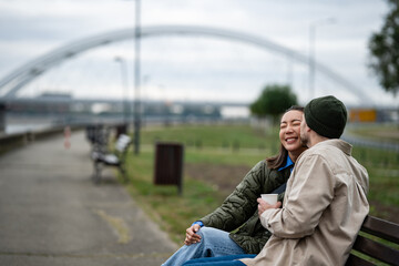 Young couple laughing together on a park bench