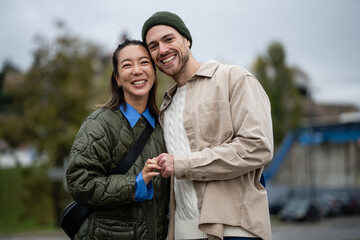 Happy multicultural couple holding hands smiling outdoors