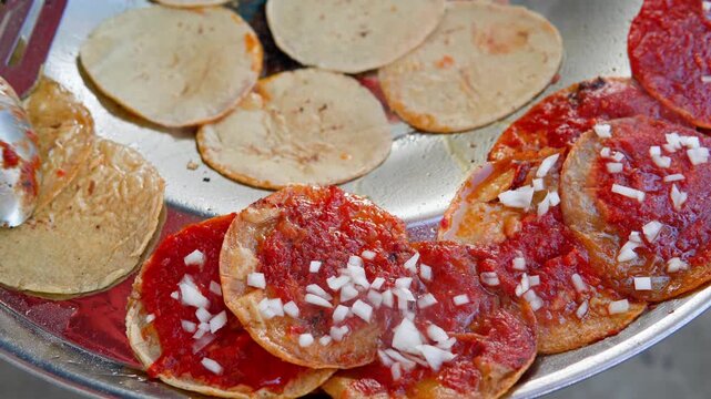 Preparing traditional mexican chalupas food with sauce and onion