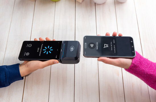 Smartphone and POS terminal performing an NFC payment, showing a processing screen during a seamless tap-to-pay transaction in a clean retail environment