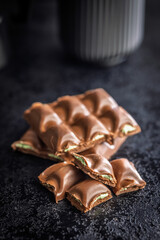 Chocolate bar with pistachios cream on black table.