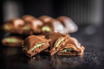 Chocolate bar with pistachios cream on black table.
