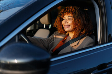 Woman driving car at sunset, expressing happiness and freedom during a road trip