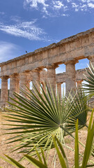 Obraz premium Ancient Stone Temple Ruins Under Bright Sky with Palm Leaves in Foreground