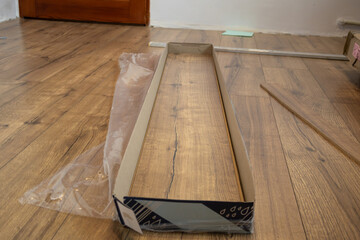 A workspace shows unpacked laminate flooring materials on a wooden floor as preparation begins for installation