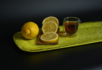 Minimalist photo emphasizing the vibrant yellow lemon and the deep color of the tea. Ideal for themes of wellness, healthy drinks, and modern cuisine.