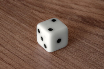 Close-up view of a standard white dice showing the numbers two, three, and five. The dice rests on a textured, old wooden background. Embodying chance and luck. Great for financial advertising.