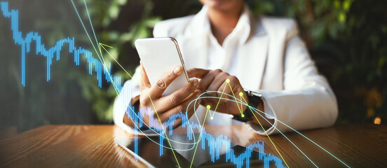 A business professional is deeply focused on reviewing market trends displayed on a mobile device. The setting combines greenery and modern decor, fostering an engaging atmosphere.