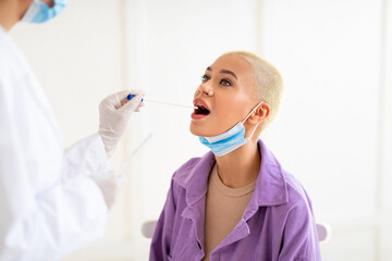 Naklejka premium Millennial lady doing pcr test, getting oral coronavirus swab test, female doctor in protective medical costume making covid-19 swab test from mouth for sick female patient