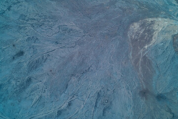 Aerial top down view of grey mountain rock texture with deep erosion channels. Natural geological terrain and rugged stone landscape background.