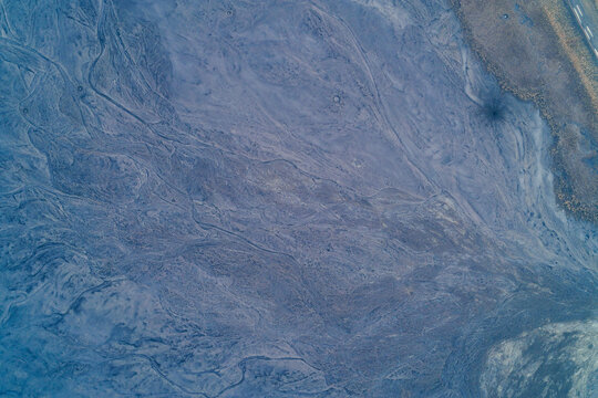 Aerial top down view of blue clay industrial dump surface with soft erosion patterns. Donbas mining waste rock texture and slag pile slope background.
