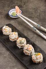 Assorted Sushi Rolls with Creamy Topping on Slate Plate and Chopsticks