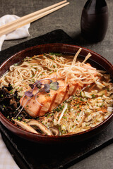 Salmon Ramen Bowl with Noodles, Vegetables, and Broth in Rustic Ceramic Dish
