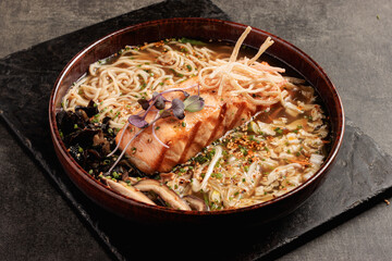 Salmon Ramen Bowl with Noodles, Vegetables, and Broth in Rustic Ceramic Dish