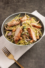 Fresh Chicken Salad Bowl with Vegetables, Nuts, and Herbs on Rustic Surface