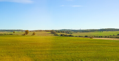 Green vast rural landscape with fields and clear blue sky showing tranquility and open space