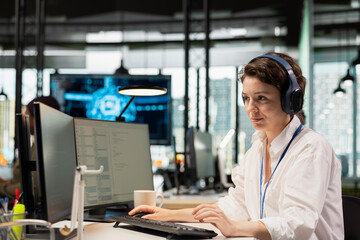 Computer scientist listening music in startup company office, testing AI deep learning algorithms. IT specialist wearing headphones scaling productivity with artificial intelligence tech on PC