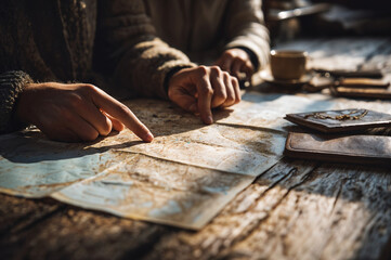 Hands Tracing a Vintage Map: Planning an Adventure on a Rustic Wooden Table with Leather Journal and Coffee