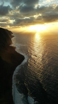 Sunset on the cliffs of Ponta do Tristan. Aerial view of coastline at sunset with ocean waves rolling in