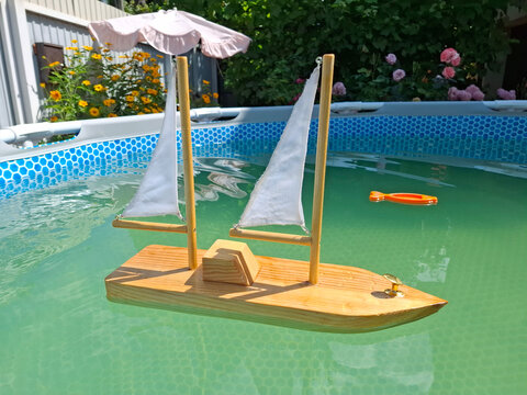 Toy wooden yacht and water thermometer in outdoor swimming pool